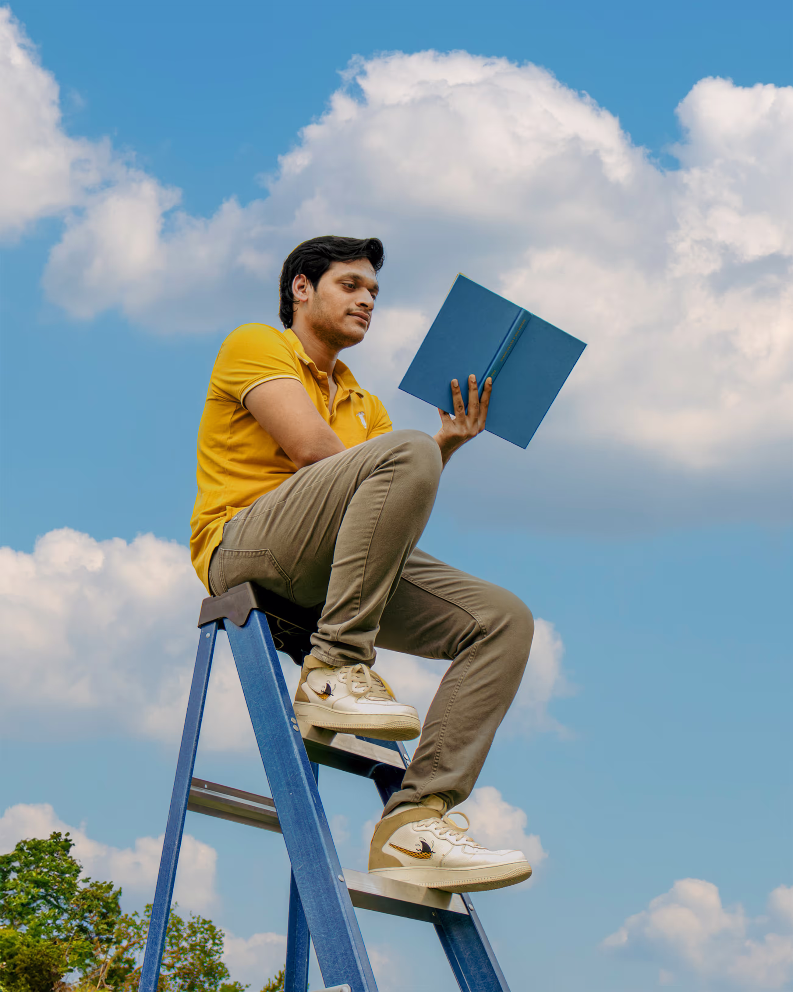 Man sitting on a ladder reading a book in cloudy background